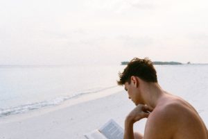 man reading on the beach signifying the best books on living in the moment