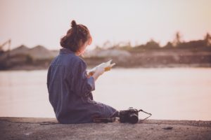 a girl sitting with a book doing creative reading