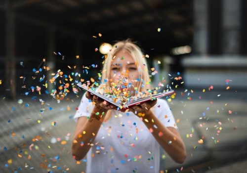 woman blowing confetti off a book